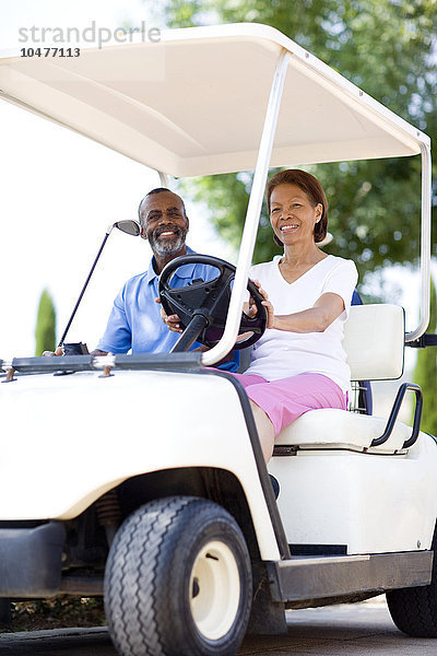 MODELL FREIGEGEBEN. Golfspieler. Mann und Frau benutzen einen Golfwagen während einer Golfrunde Golfspieler