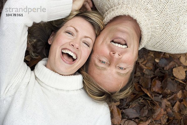 Lachendes Paar auf Herbstblättern liegend