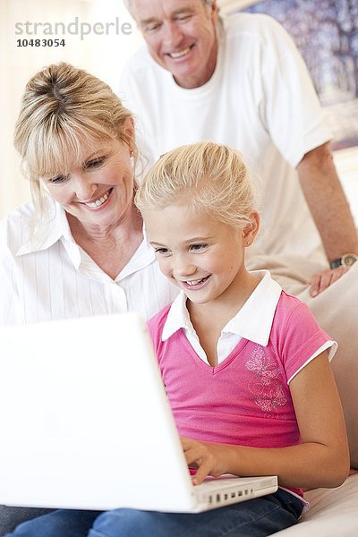 MODELL FREIGEGEBEN. Großeltern und Enkelin benutzen einen Laptop Großeltern und Enkelin