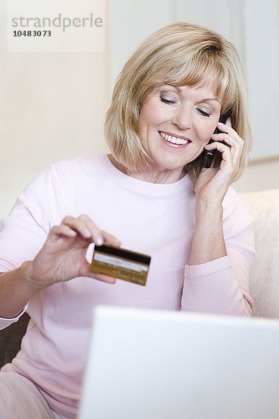 MODELL FREIGEGEBEN. Kauf mit Kreditkarte. Ältere Frau  die eine Kreditkarte benutzt  um einen Kauf über das Telefon zu tätigen Kauf mit Kreditkarte