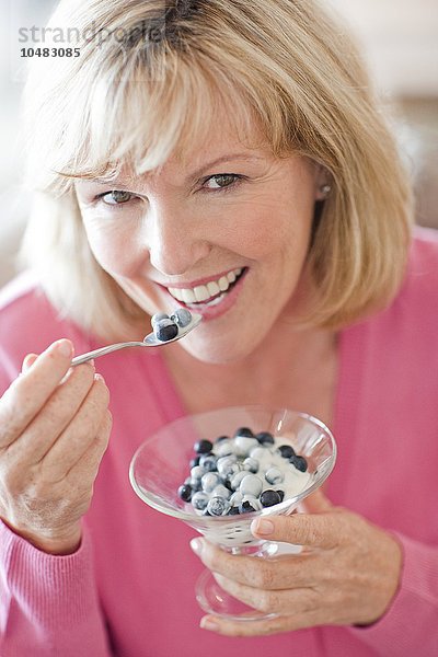 EIGENSCHAFT FREIGEGEBEN. MODELL FREIGEGEBEN. Gesunde Ernährung. Ältere Frau isst Blaubeeren und Joghurt Gesunde Ernährung