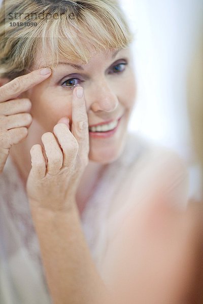 MODELL FREIGEGEBEN. Ältere Frau setzt Kontaktlinsen ein Ältere Frau setzt Kontaktlinsen ein