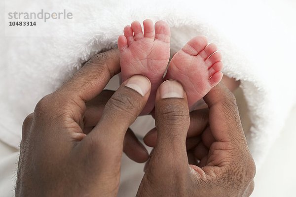 MODELL FREIGEGEBEN. Die Füße eines Babys. Füße eines drei Wochen alten Babys in den Händen seines Vaters Baby's feet