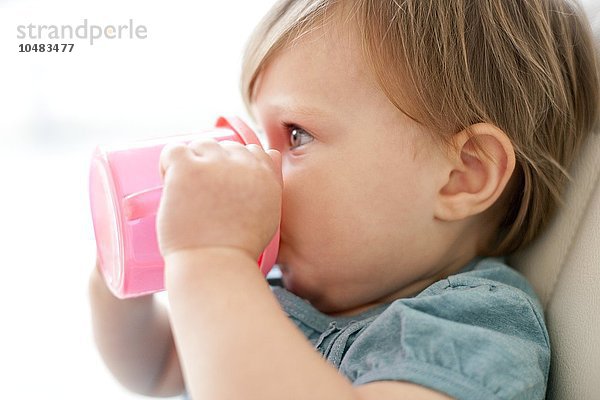 MODELL FREIGEGEBEN. Kleinkind trinkt. 15 Monate altes Mädchen trinkt aus einer Trainingstasse Kleinkind trinkt