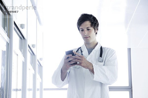 Arzt  der ein Mobiltelefon benutzt Arzt  der ein Mobiltelefon benutzt