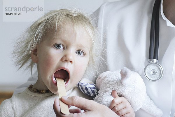 MODELL FREIGEGEBEN. Pädiatrische Untersuchung. Arzt benutzt einen Zungenspatel Pädiatrische Untersuchung