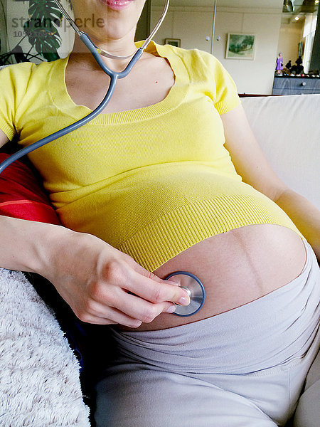 Eine schwangere Frau mit einem Stethoskop.