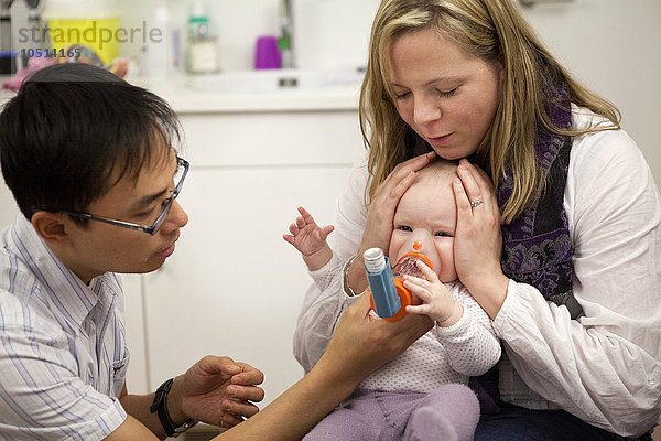 Reportage in einer Kinderarztpraxis in Lausanne  Schweiz. Die Kinderärztin hilft einem an Asthma leidenden Baby beim Inhalieren eines Bronchodilatators.