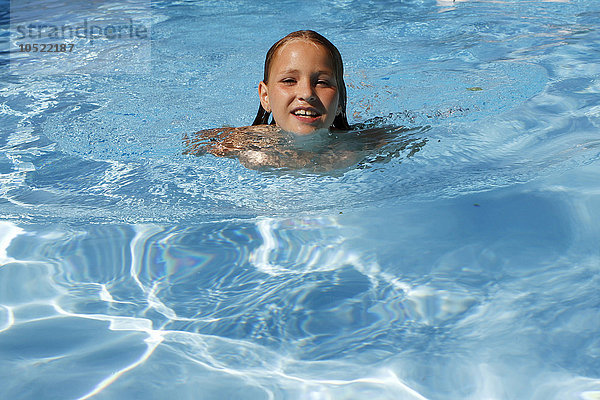 Ein 10-jähriges Mädchen schwimmt in einem Schwimmbad.