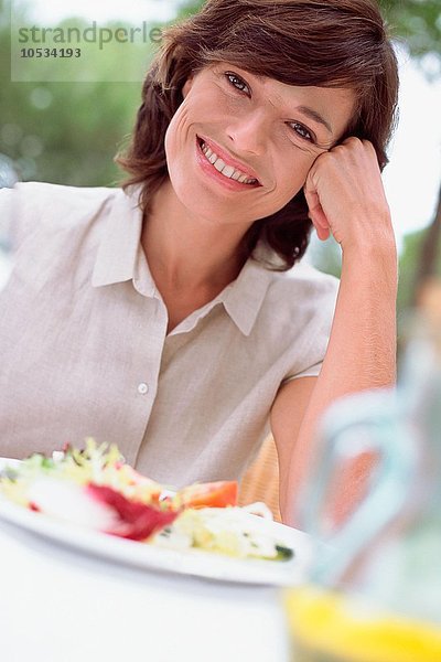 Lächelnde Frau beim Mittagessen