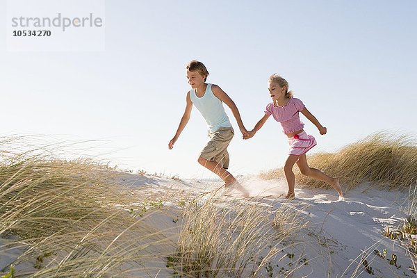 Junge und Mädchen laufen auf Sanddüne