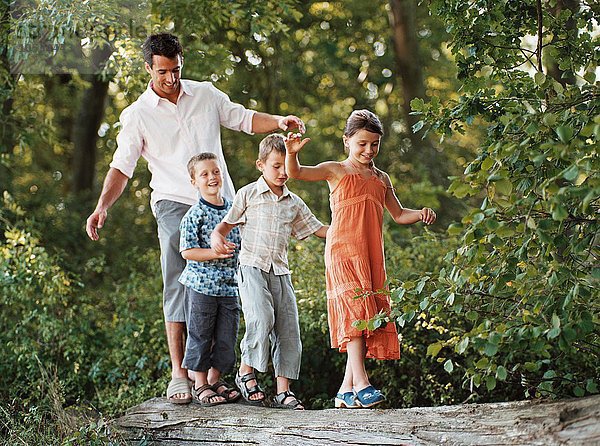 Kinder und Vater gehen auf einem Holzklotz