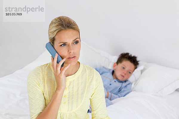 Kranker Junge und Mutter am Telefon