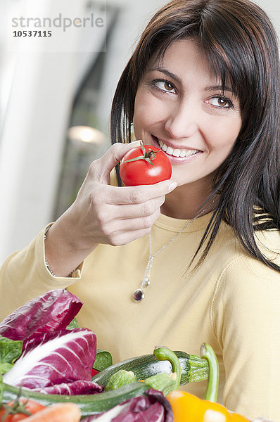 Lächelnde Frau mit Tomate und Gemüse