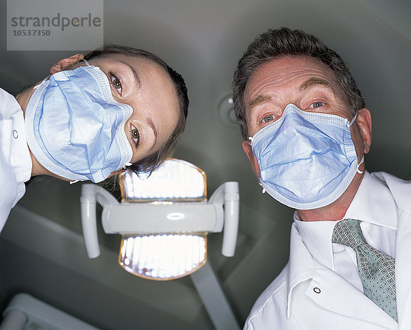 Niederwinkelansicht von Zahnarzt und Assistentin in chirurgischen Masken