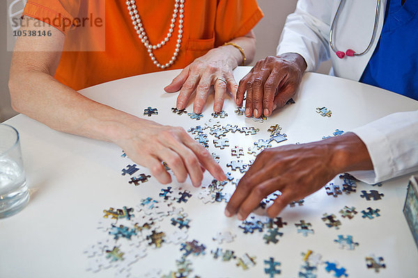Seniorin und Ärztin mit Puzzle