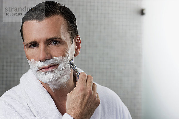 Mann beim Rasieren im Bad