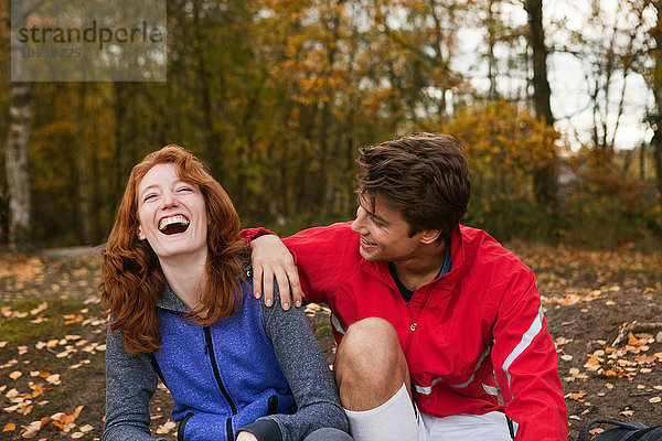 Junges Paar in Sportbekleidung lacht im Wald