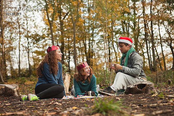 Junge Freunde im Wald mit Weihnachtsmützen und -kronen