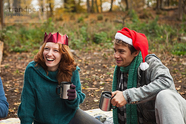 Junges Paar mit Weihnachtsmützen und Kronen im Wald