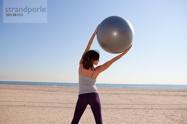 Frau am Strand mit Übungsball