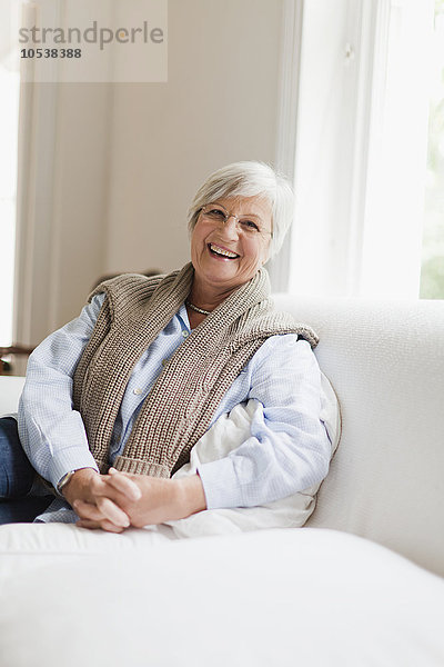 Lächelnde ältere Frau auf der Couch sitzend