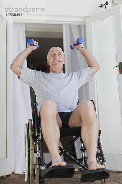 Älterer Mann im Rollstuhl beim Heben von Gewichten