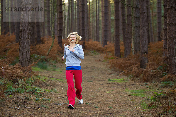 Lächelnde Frau  die im Wald rennt