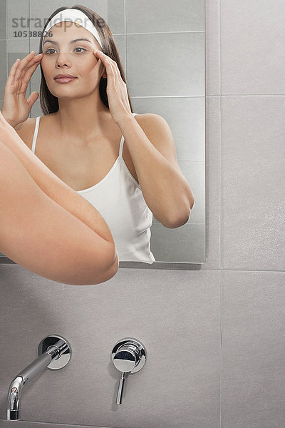 Frau untersucht ihr Gesicht im Spiegel