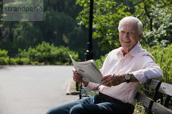 Porträt eines älteren Mannes  der Zeitung liest  lächelnd
