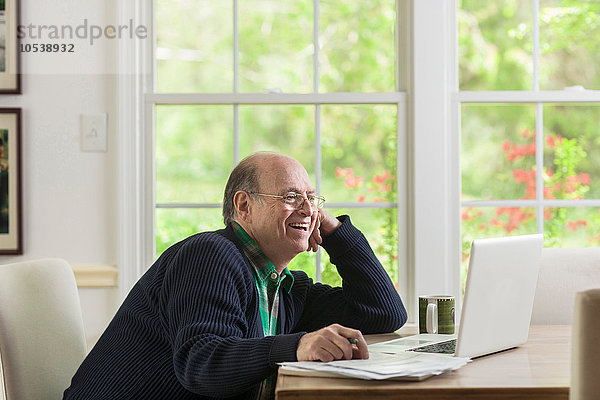 Senior Mann mit Laptop zu Hause  lächelnd