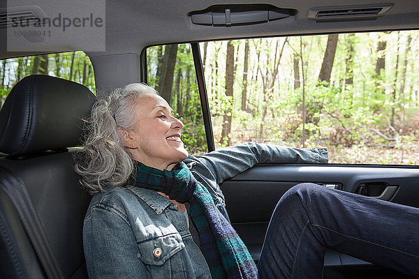 Seniorin entspannt auf dem Rücksitz des Autos