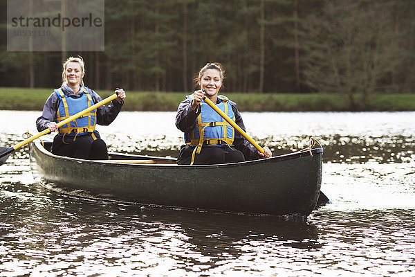 Frauen rudern Kanu auf stillem See