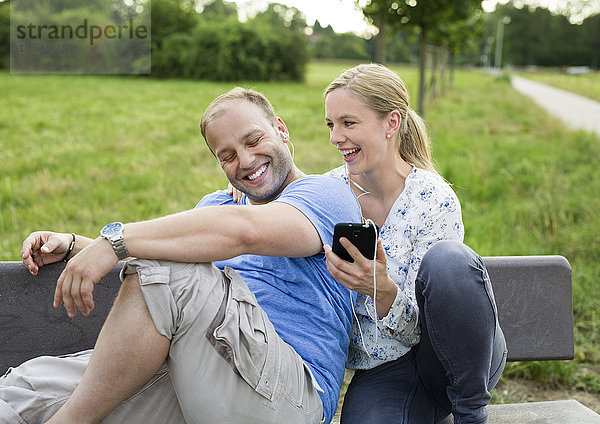 Fröhliches Paar sitzt auf einer Bank