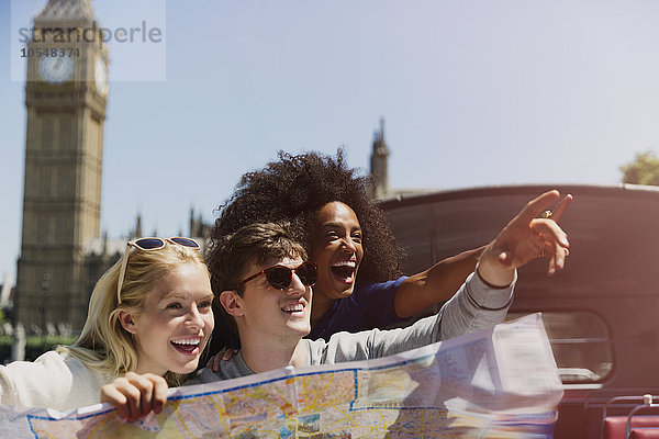 Enthusiastische Freunde mit Karte unter dem Big Ben-Uhrturm in London