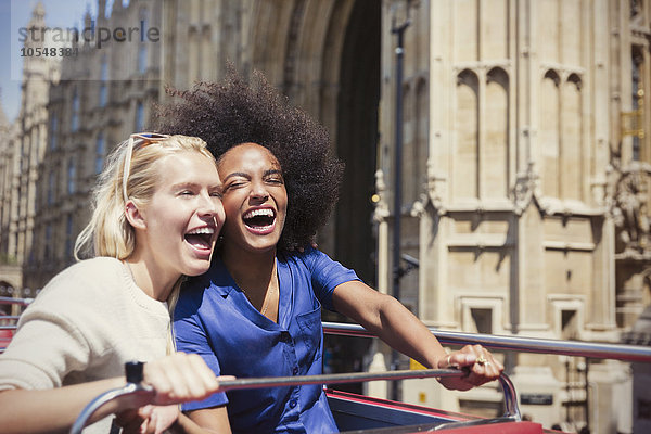 Begeisterte Freunde lachen im Doppeldeckerbus in London