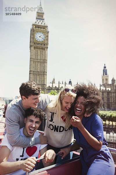 Enthusiastische Freunde im Doppeldeckerbus unter dem Big Ben-Uhrturm  London  Großbritannien