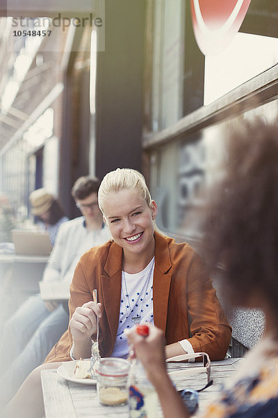 Lächelnde Freunde essen Dessert auf dem Bürgersteig Cafe