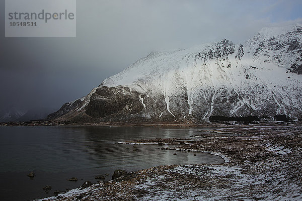 Schneebedeckte Berge über dem kalten See  Norwegen