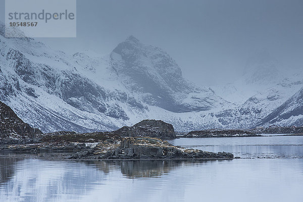 Schneebedeckte zerklüftete Berge über kalter Bucht  Norwegen