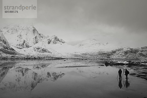Fotografen unter schneebedeckten Bergen und ruhiger Bucht  Norwegen