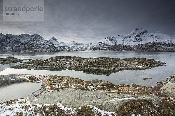 Schneebedeckte Bergkette hinter zerklüfteter Bucht  Sund  Lofoten Inseln  Norwegen