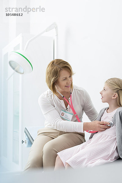 Kinderarzt mit Stethoskop bei Patientin im Untersuchungsraum
