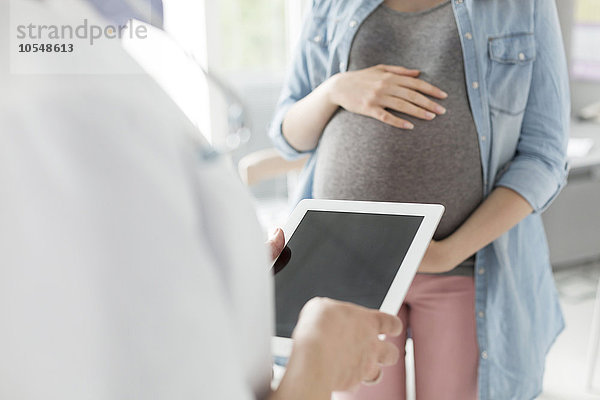 Arzt mit digitaler Tablette im Gespräch mit Schwangeren