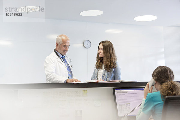 Arzt und Teenager-Patient besprechen die Krankenakte auf der Krankenstation