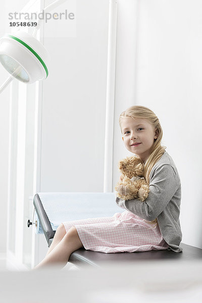 Portrait lächelndes Mädchen Patientin umarmt Teddybär im Untersuchungszimmer