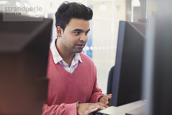 Mann beim Tippen am Computer im Klassenzimmer der Erwachsenenbildung