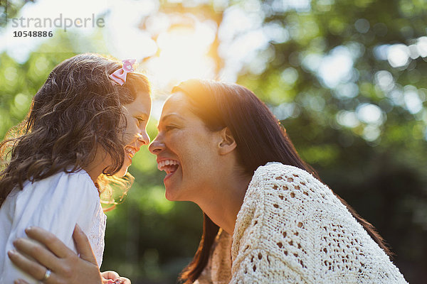 Begeisterte Mutter und Tochter lächeln von Angesicht zu Angesicht