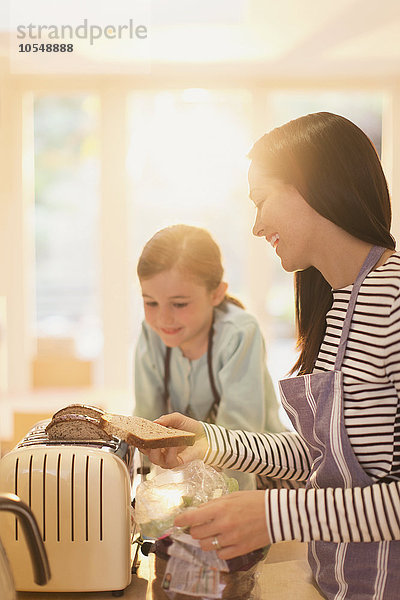 Mutter und Tochter toasten Brot in der Küche