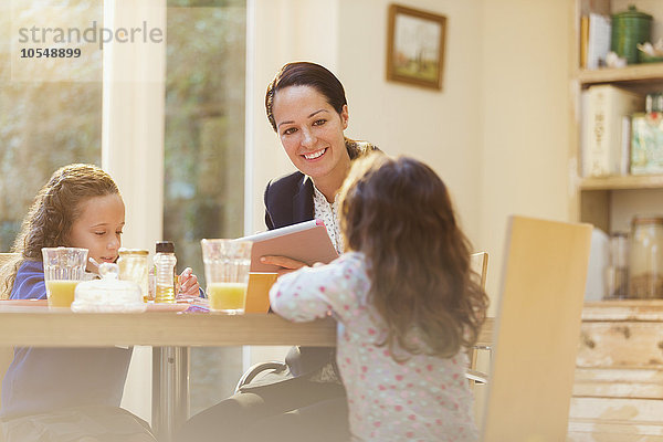 Arbeitende Mutter und Töchter am Frühstückstisch